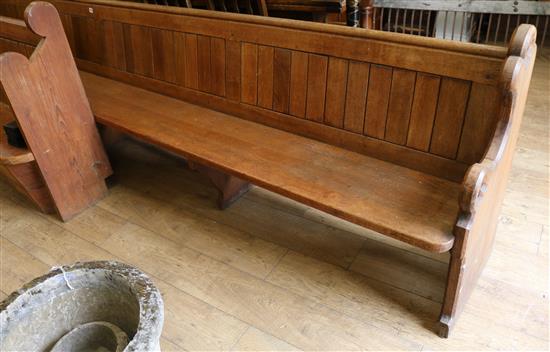 A late 19th century long oak pew, L. 427cm